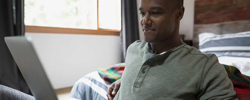 A man sits with a laptop, ready to make a claim online.